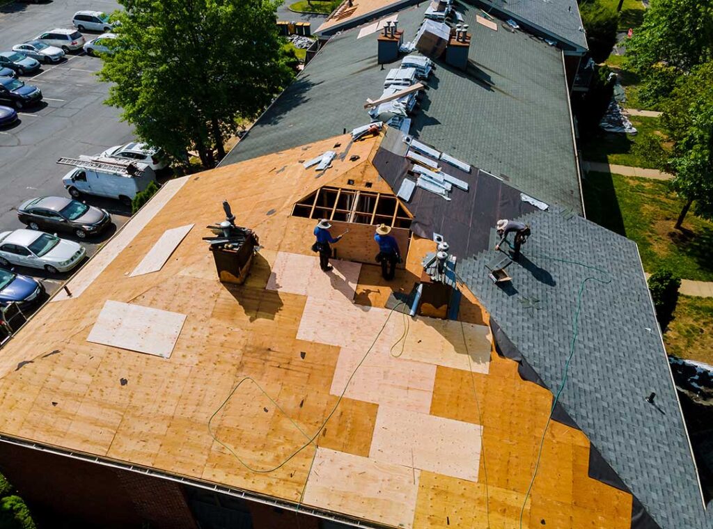 Water stain beneath a roof leak with damaged shingles and a bucket catching drips indoors